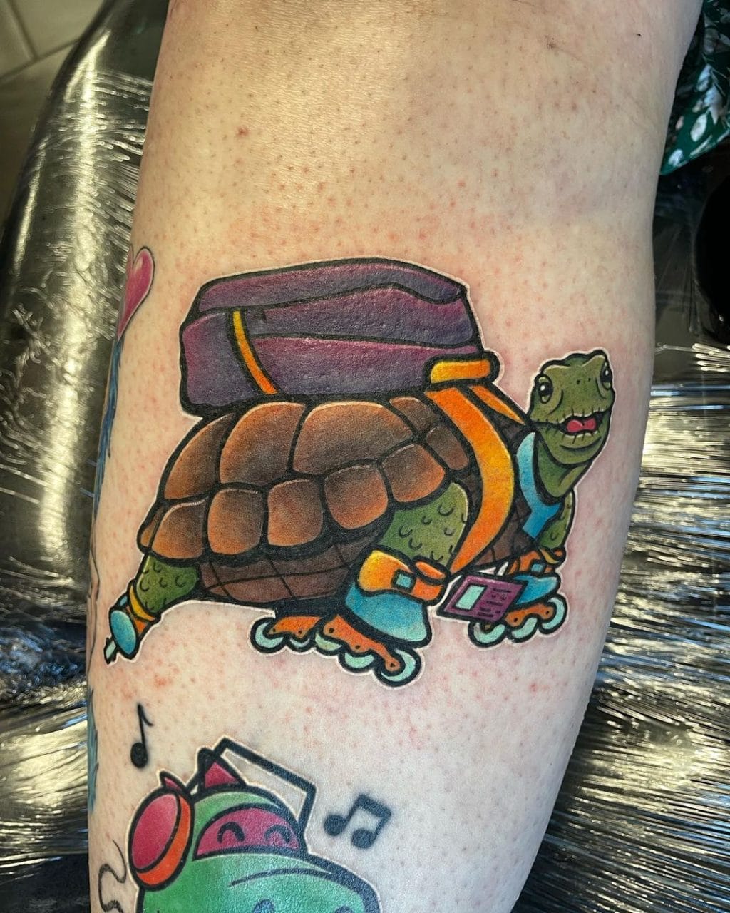 Playful color tattoo of a tortoise on rollerblades wearing a backpack