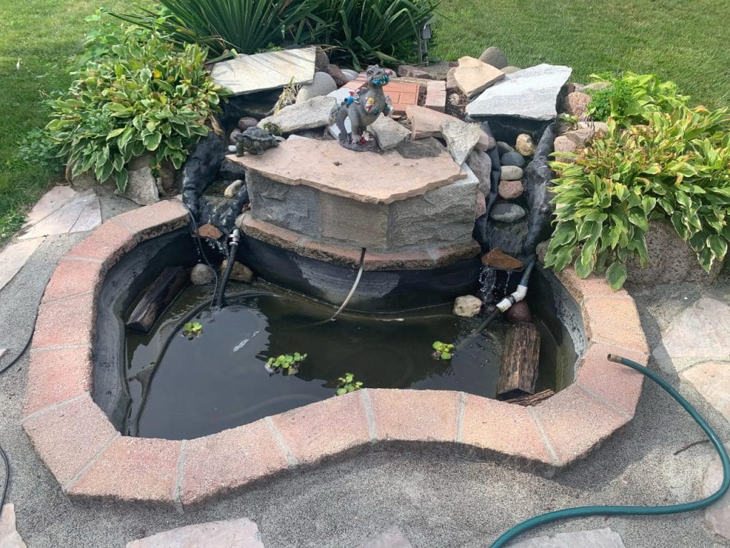 Outdoor turtle pond with multi-tiered stone fountain on a brick patio