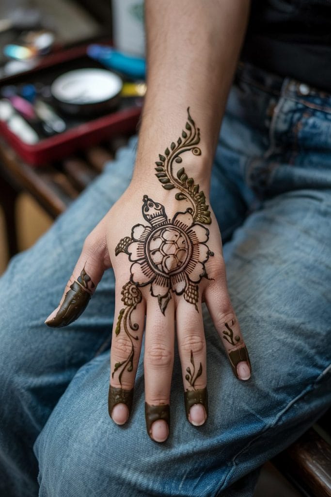 Floral flow turtle henna design framed by leafy vines on the hand