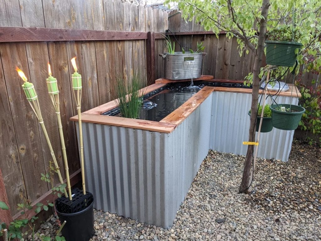 Corrugated metal L-shape above ground turtle pond with wooden trim and waterfall feature