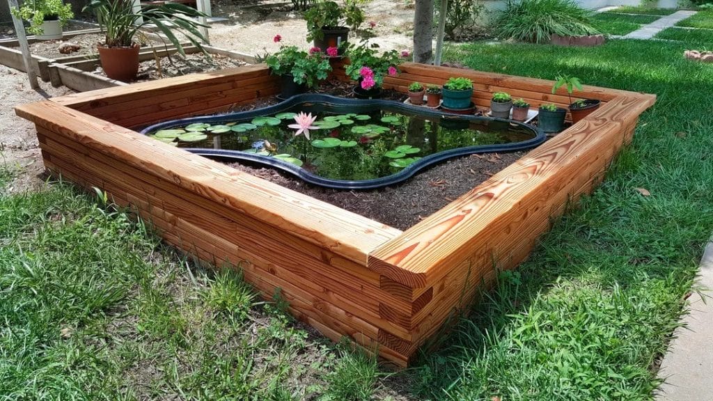Preformed pond liner above ground turtle pond inside a wooden box with surrounding plants