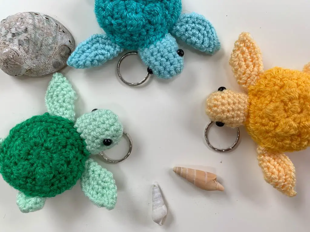 Small crochet turtle keychains in teal, green and yellow, an easy beginner pattern