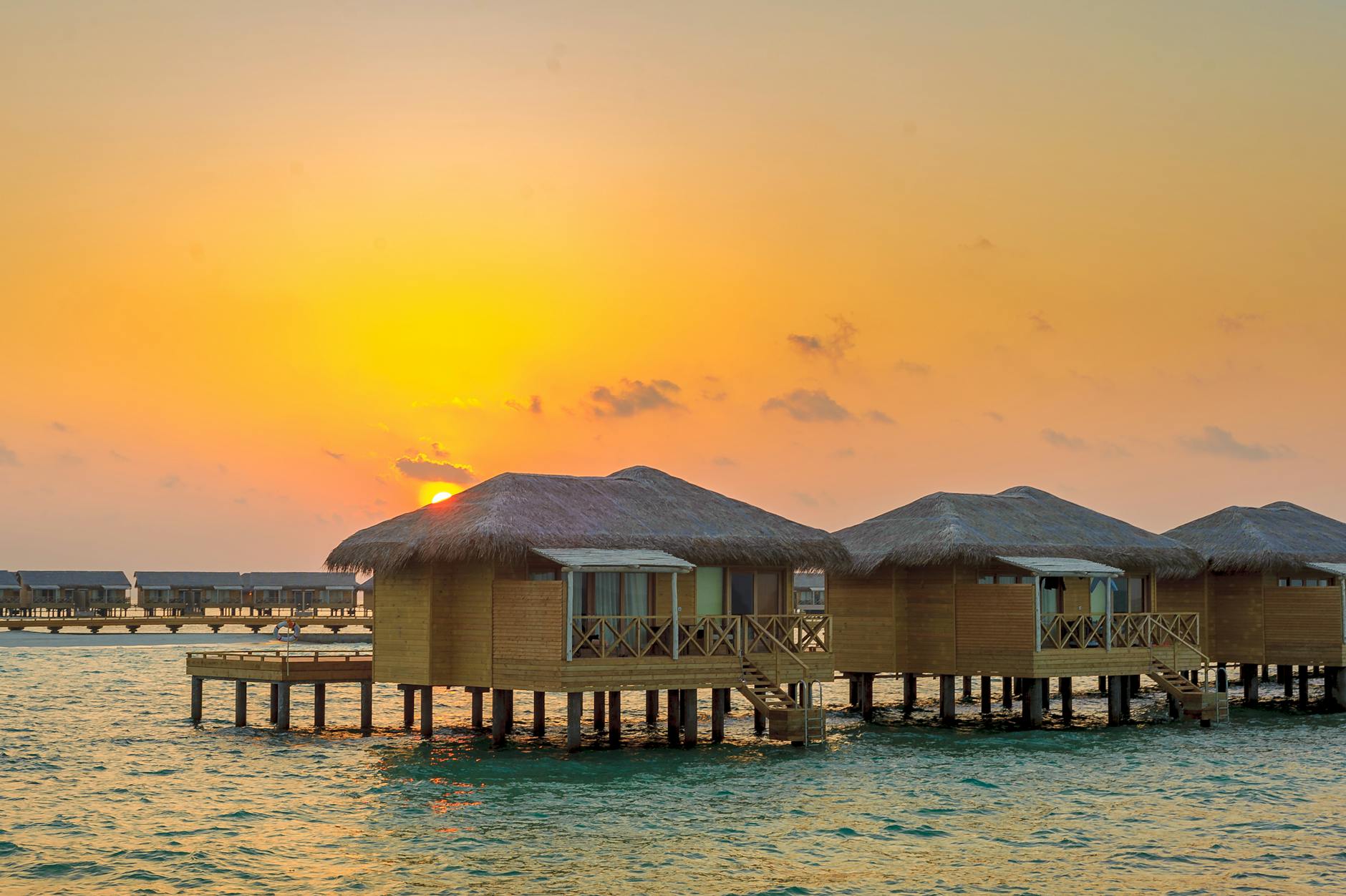 Overwater villa on a turquoise lagoon in the Maldives, where sea turtles cruise the house reef