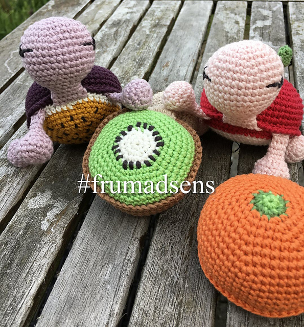 Crochet passion fruit turtle amigurumi alongside kiwi and orange fruit shells