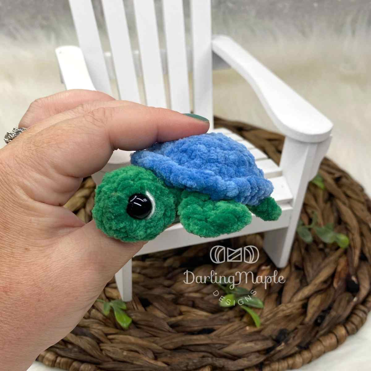 Chubby green and blue velvet no-sew crochet jelly bean turtle held in a hand