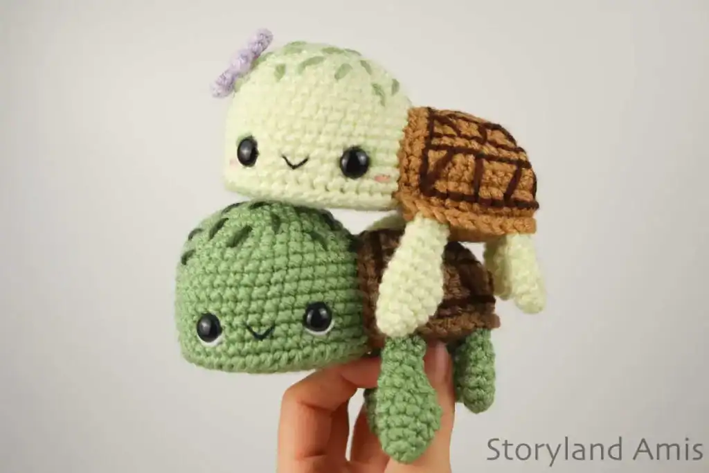 Green crochet sea turtle with an embroidered face and a segmented brown shell