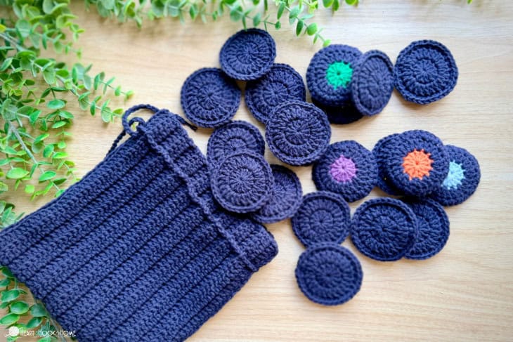 Navy crochet memory match game tiles with colored centers spilling from a drawstring bag by Heart Hook Home